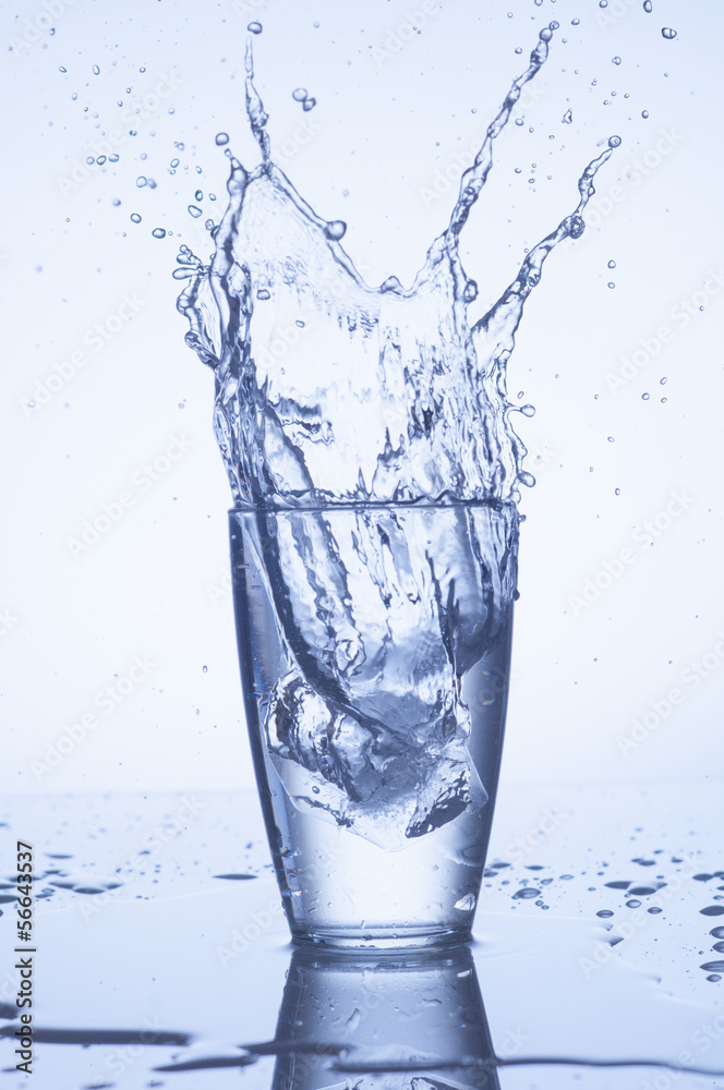 Splash of water in glass with drops on light background Splash of water in glass with drops on light background
