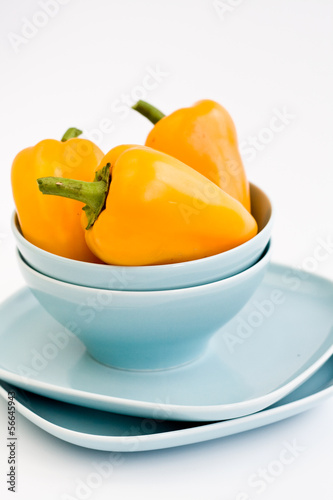 Three yellow sweet peppers are on blue plates