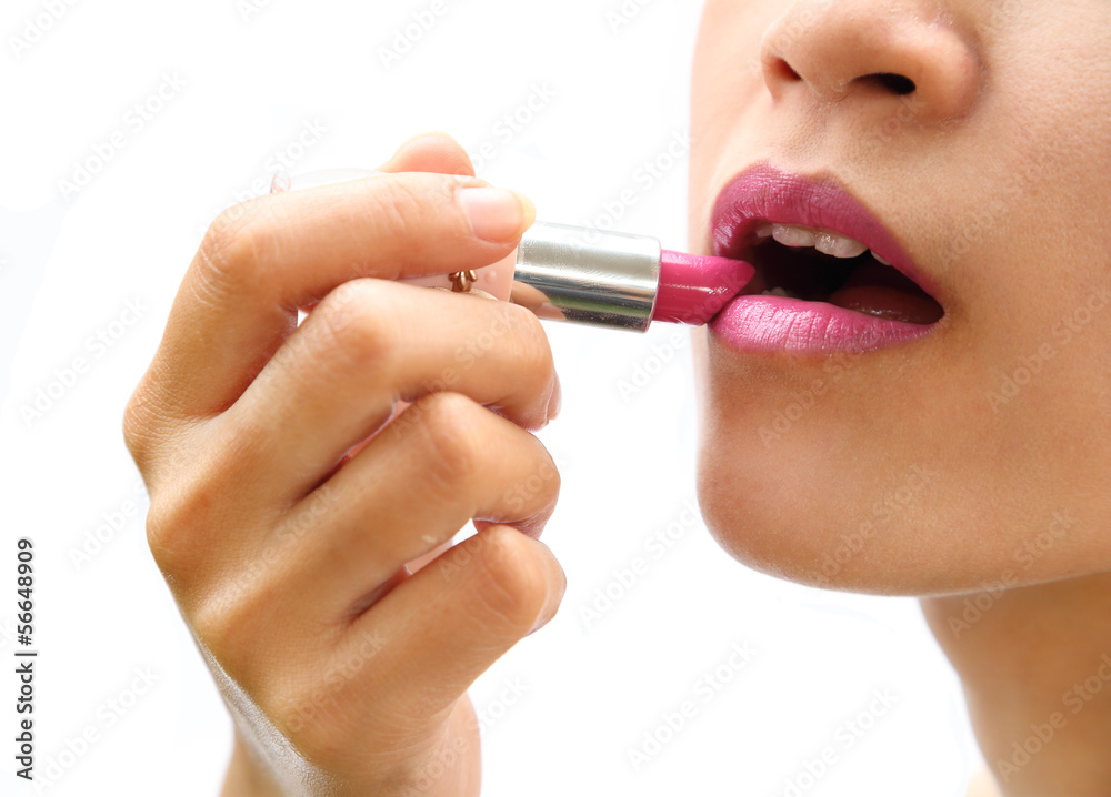 beautiful woman is applying her lips with pink lipstick on white