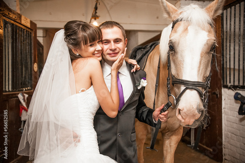 Young bride hugging groom holding horse