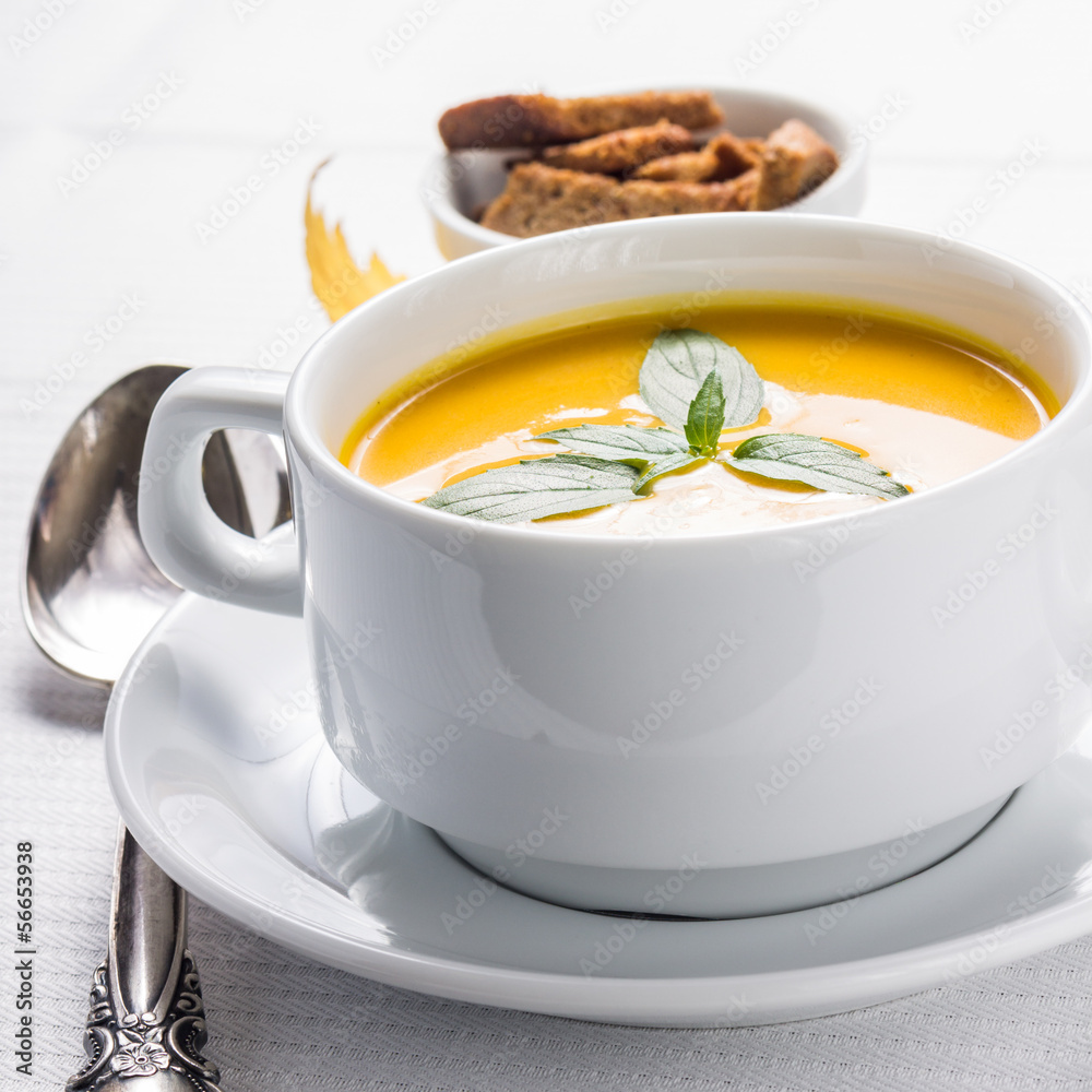 Pumpkin cream-soup in white bowl with silver spoon Pumpkin cream-soup in white bowl with silver spoon