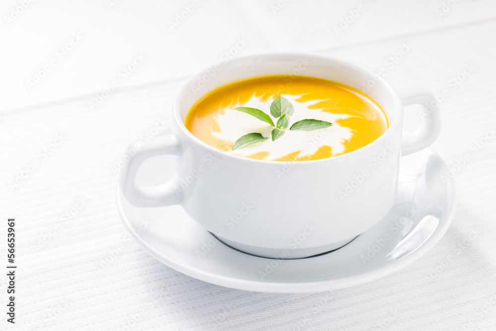 Pumpkin soup with basil on served table Pumpkin soup with basil on served table
