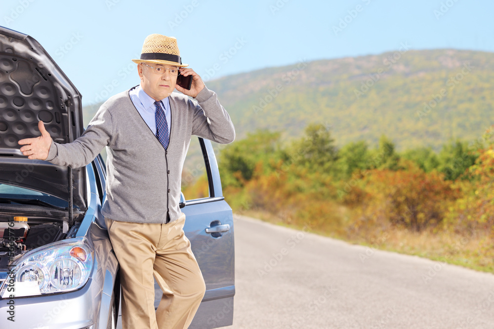 Nervous senior man on a broken car talking on a phone Nervous senior man on a broken car talking on a phone