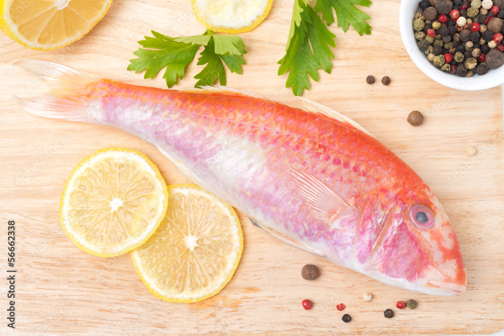 fresh surmullet, lemon and spices on a wooden board fresh surmullet, lemon and spices on a wooden board