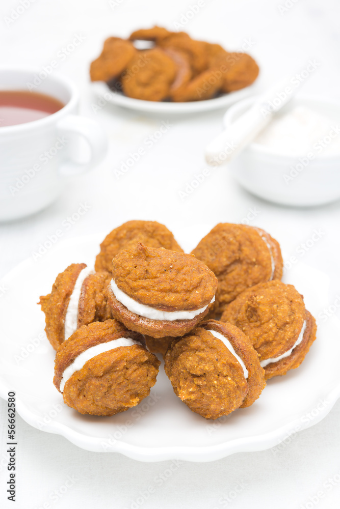 Pumpkin cookies with cream filling on a white plate and tea Pumpkin cookies with cream filling on a white plate and tea