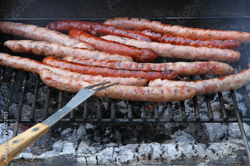Fresh sausages grilling outdoors on a charcoal barbecue grill