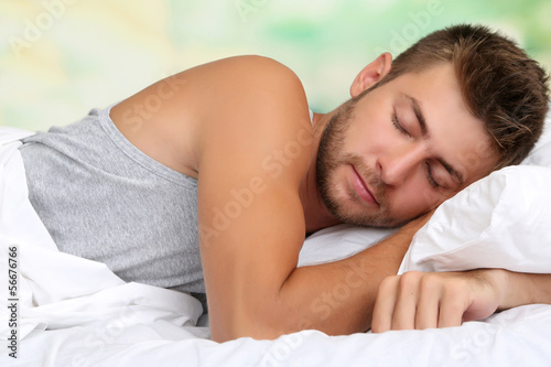 Handsome young man in bed  on bright background  close-up