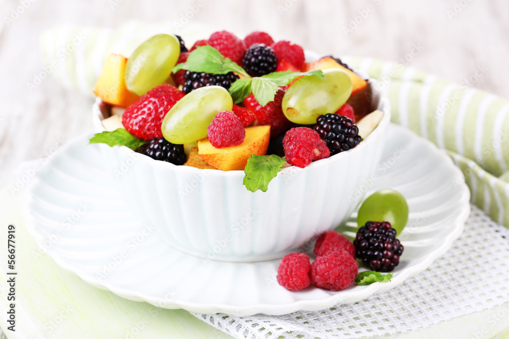 Fruit salad in bowl, on wooden background