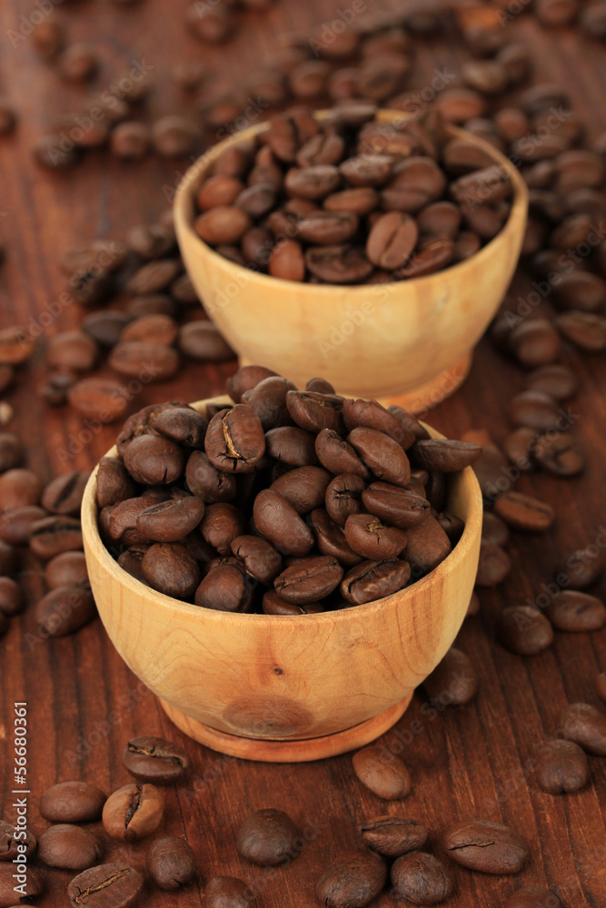 Fototapeta premium Roasted coffee beans in wooden bowls on dark wood table, aromatic beverage ingredient for morning drink
