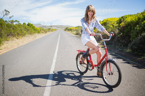 Smiling young model posing while riding bike