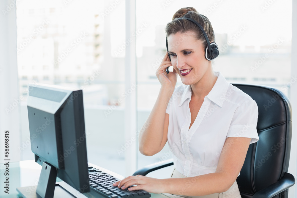 Cheerful call centre agent working on computer while having a ca