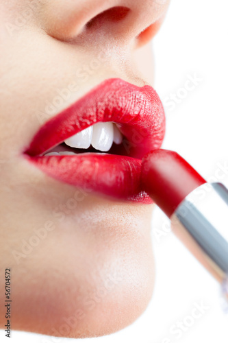 Extreme close up on gorgeous model applying red lipstick