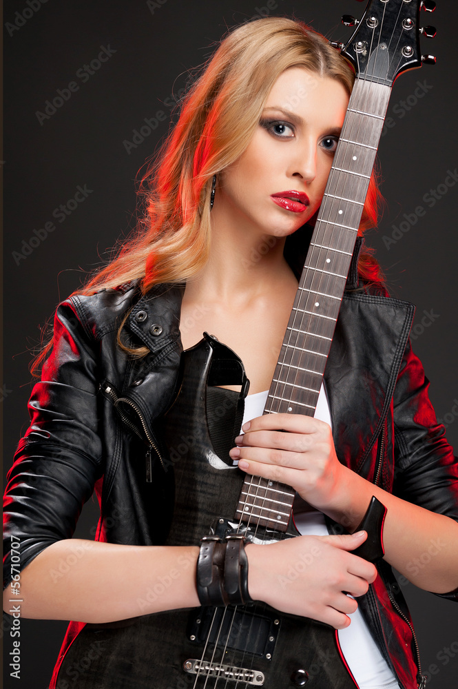 Guitar girl. Beautiful young woman holding guitar and looking at