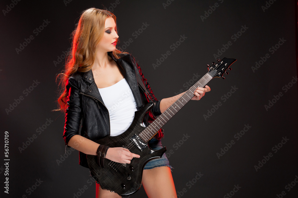 Guitar girl. Beautiful young woman playing guitar and looking aw Guitar girl. Beautiful young woman playing guitar and looking aw