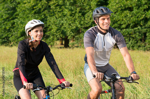 Young Couple Riding Bicycle In Meadow