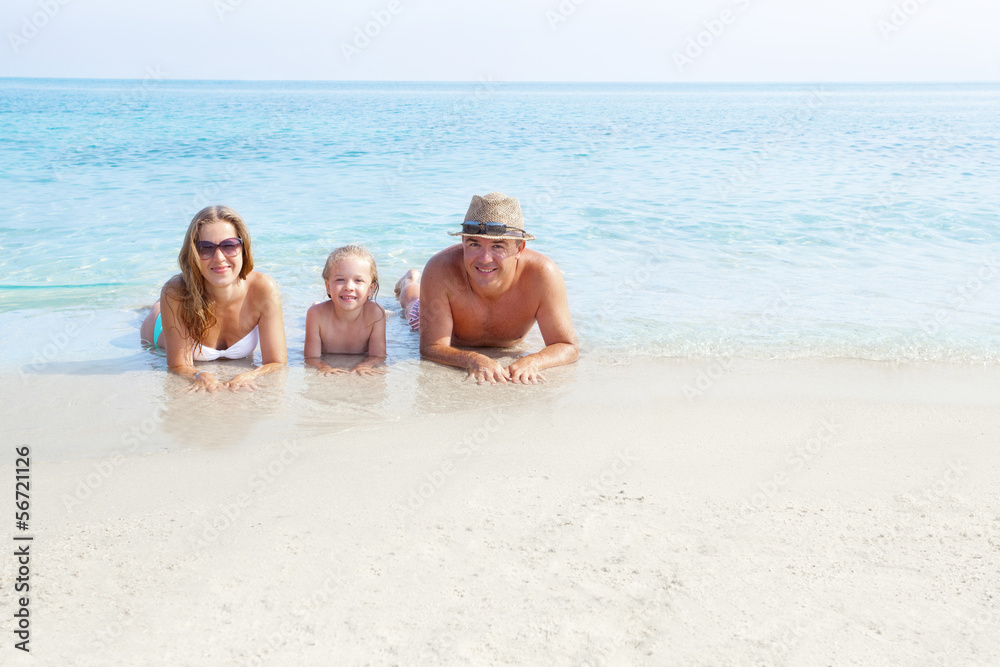 Fototapeta premium Happy family laying on the sand enjoying the ocean