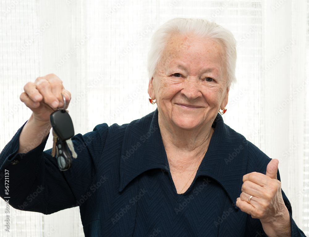 Senior woman with a car key and making OK gesture