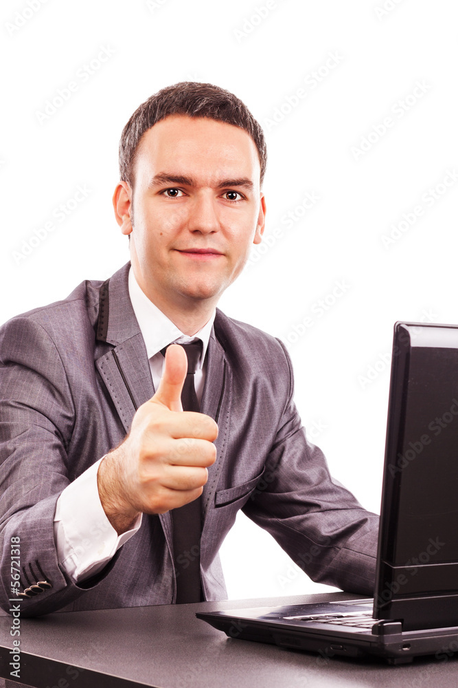 Young businessman sitting at office desk showing his thumb up Young businessman sitting at office desk showing his thumb up