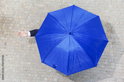 Confident businessman hidden under umbrella and checking if it's