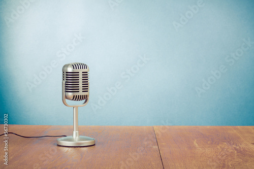 Retro style microphone on table in front aquamarine background