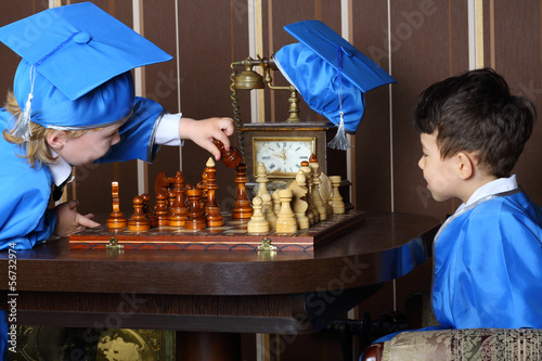 Two boys in blue suits start to a game of chess photo