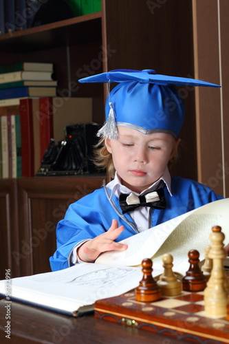 A befuddled little boy leafs through a book photo