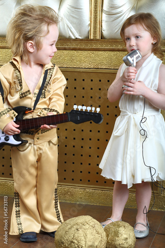 A little girl sings a song and pop musician plays guitar