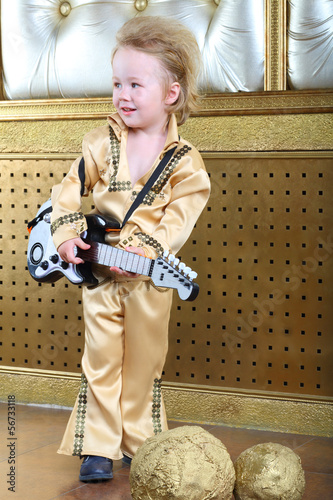 A small boy in pop retro suit with guitar