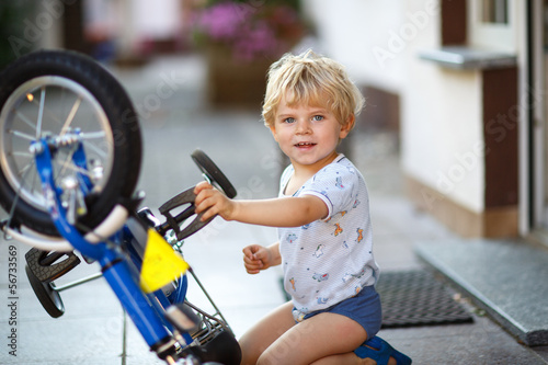 Little toddler boy repairing his first bike