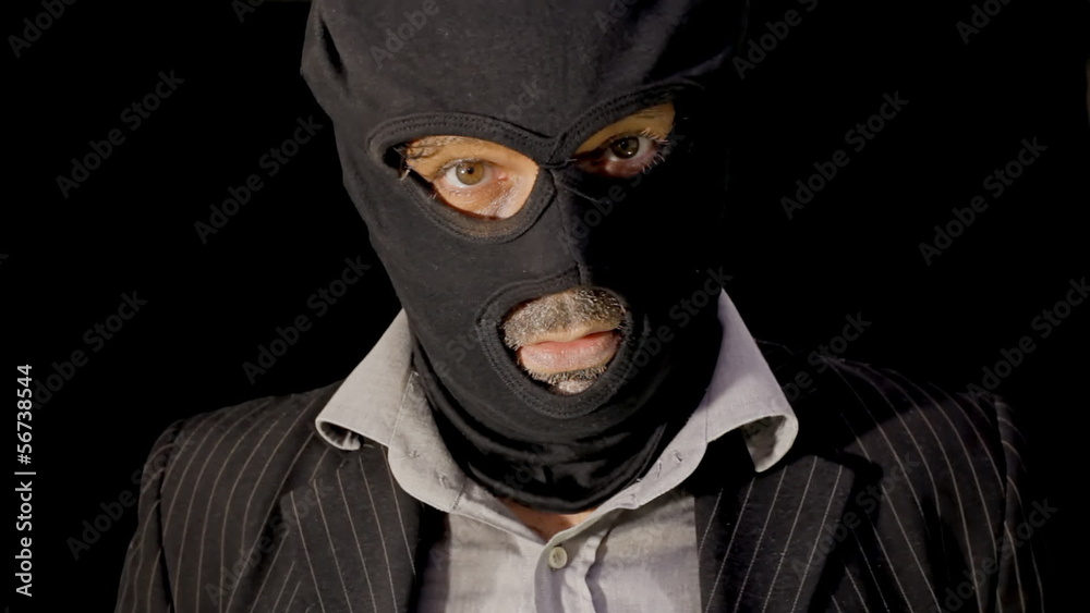Masked criminal showing up laughing close up Masked criminal showing up laughing close up