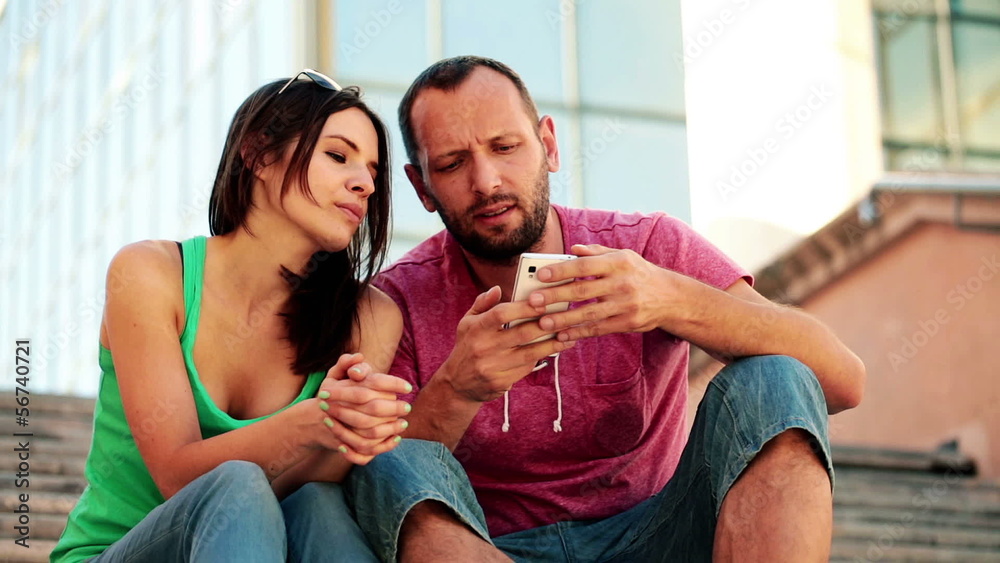 Couple with smartphone sitting on stairs in the city Couple with smartphone sitting on stairs in the city