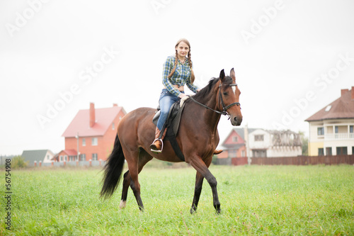 A girl rides a horse on the field