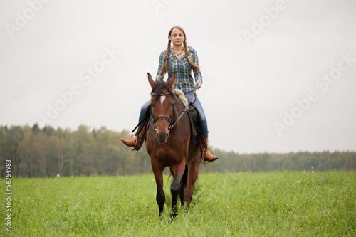 A girl rides a horse on the field