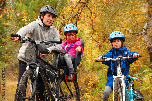 Happy family on bikes in autumn park, having fun