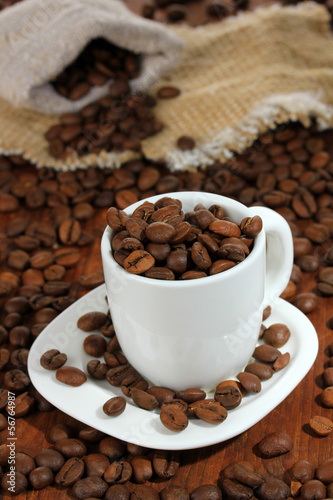 Coffee beans in cup on wooden background