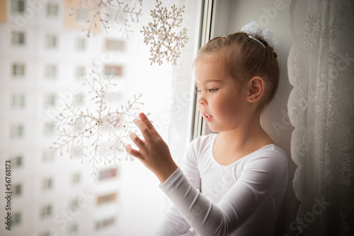 Girl sticks a snowflake on the window