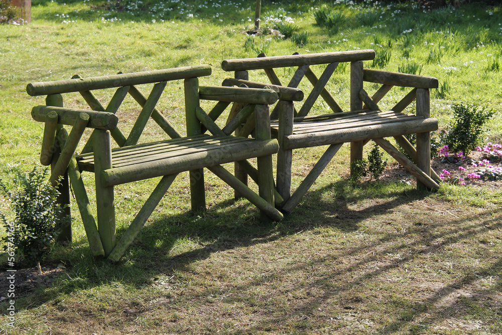 Two Wooden Rustic Seats in a Garden Setting. Two Wooden Rustic Seats in a Garden Setting.