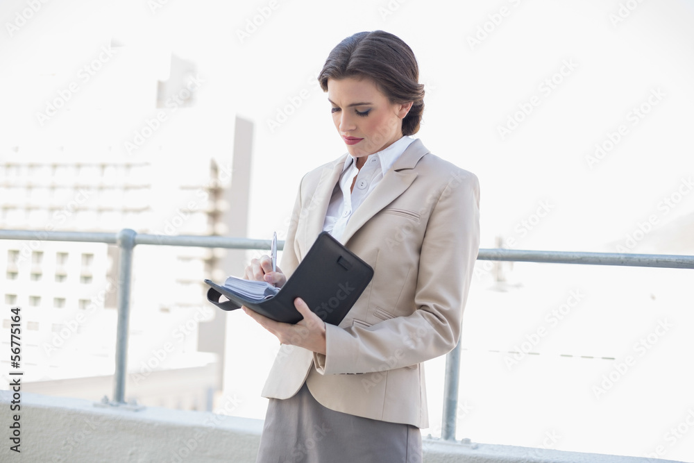 Concentrated stylish brown haired businesswoman filling her sche Concentrated stylish brown haired businesswoman filling her sche