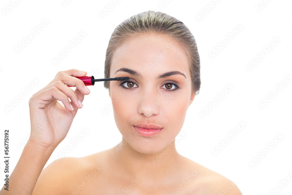 Content young brunette woman applying mascara