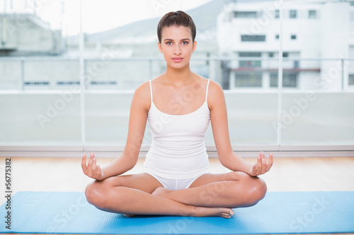 Calm natural brown haired woman in white sportswear practicing y