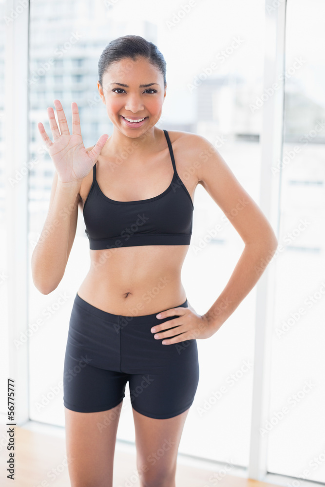 Joyful dark haired model in sportswear posing and greeting the c