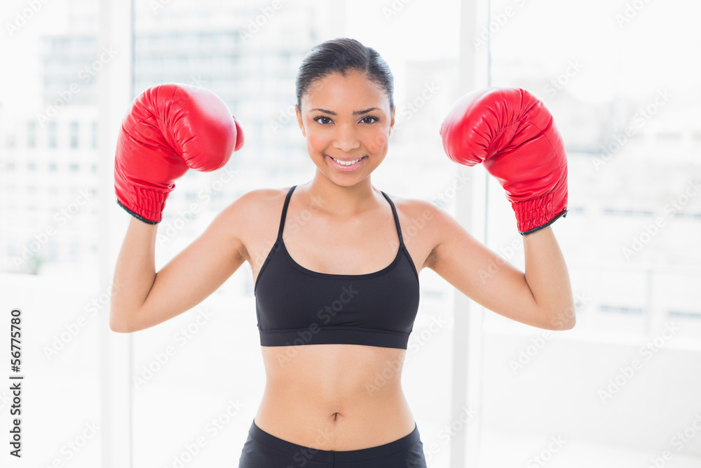 Lovely dark haired model in sportswear wearing red boxing gloves