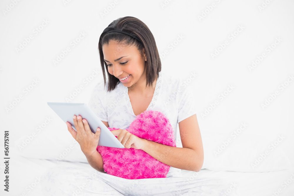 Concentrated young dark haired model holding a pillow and using Concentrated young dark haired model holding a pillow and using