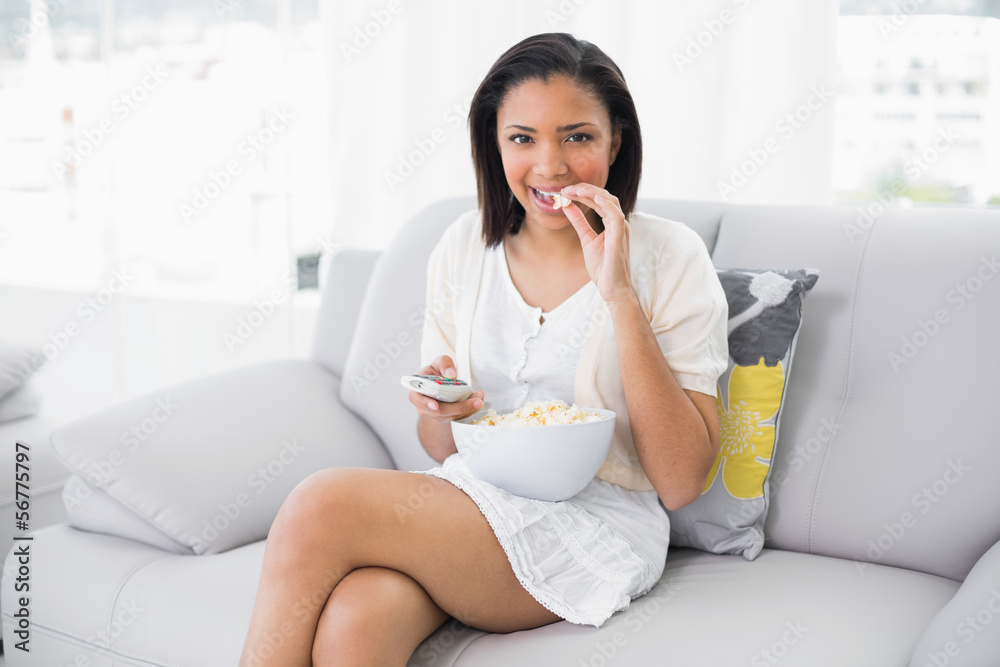 Cute young dark haired woman in white clothes eating popcorn whi Cute young dark haired woman in white clothes eating popcorn whi