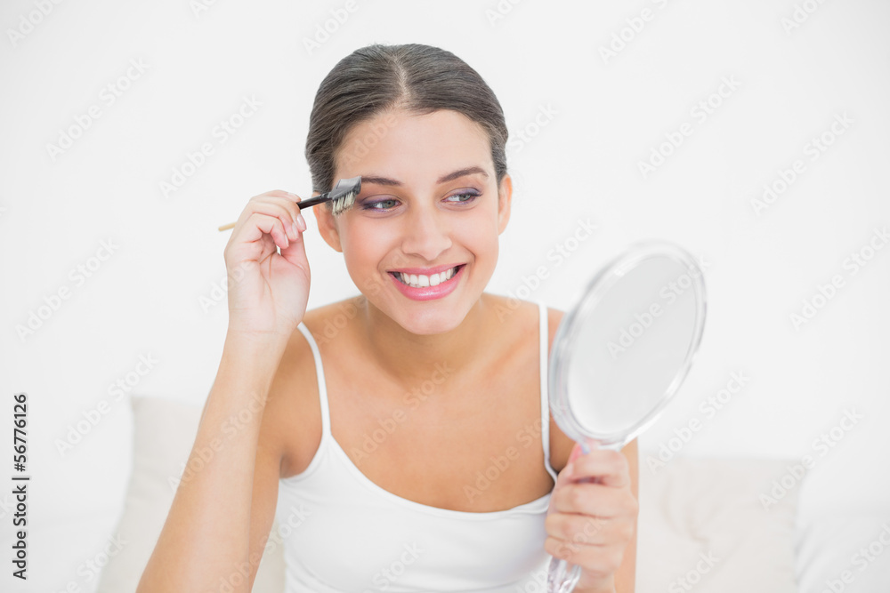 Pleased young brown haired model in white pajamas plucking her e Pleased young brown haired model in white pajamas plucking her e