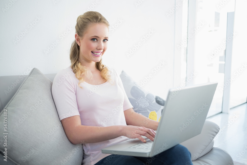 Casual happy blonde sitting on couch using laptop Casual happy blonde sitting on couch using laptop