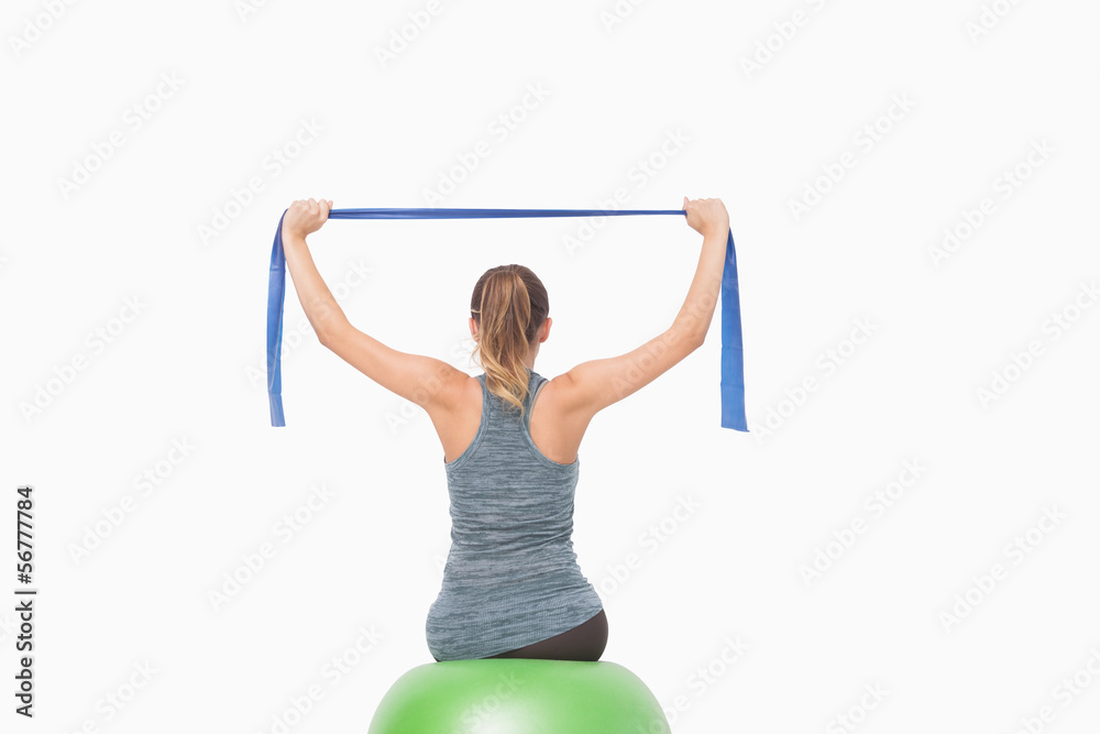Naklejka premium Ponytailed woman training using a resistance band sitting on a f