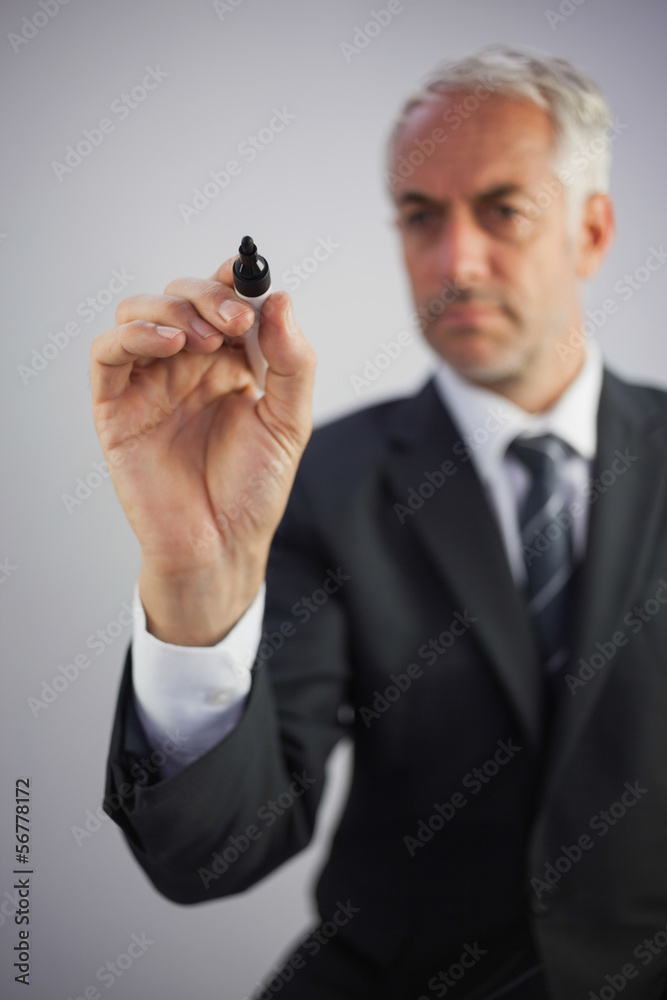 Serious businessman holding a marker and writing Serious businessman holding a marker and writing