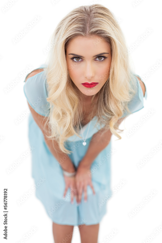 Serious blonde model in blue dress posing hands on the thighs Serious blonde model in blue dress posing hands on the thighs