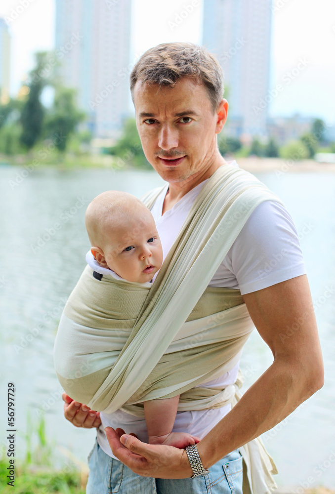 Father carrying his son in sling outdoors
